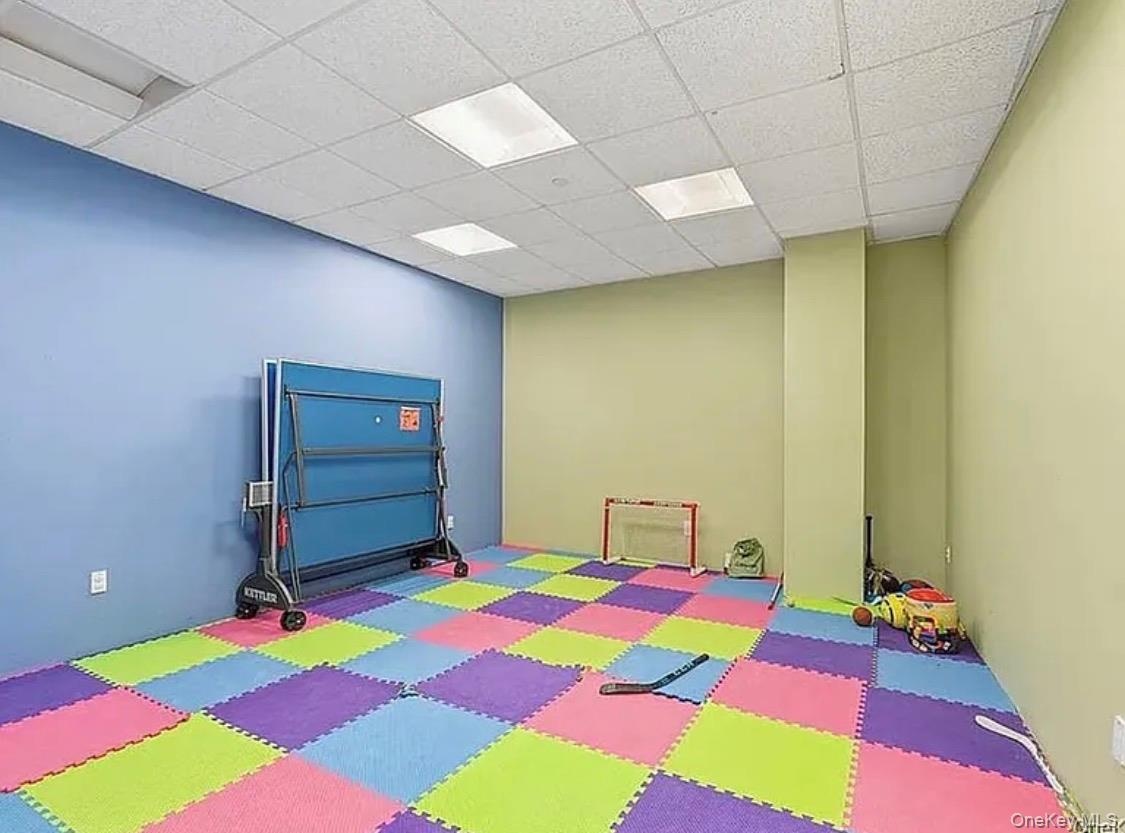 Recreational room featuring colorful interlocking floor mats and a drop ceiling with integrated lighting