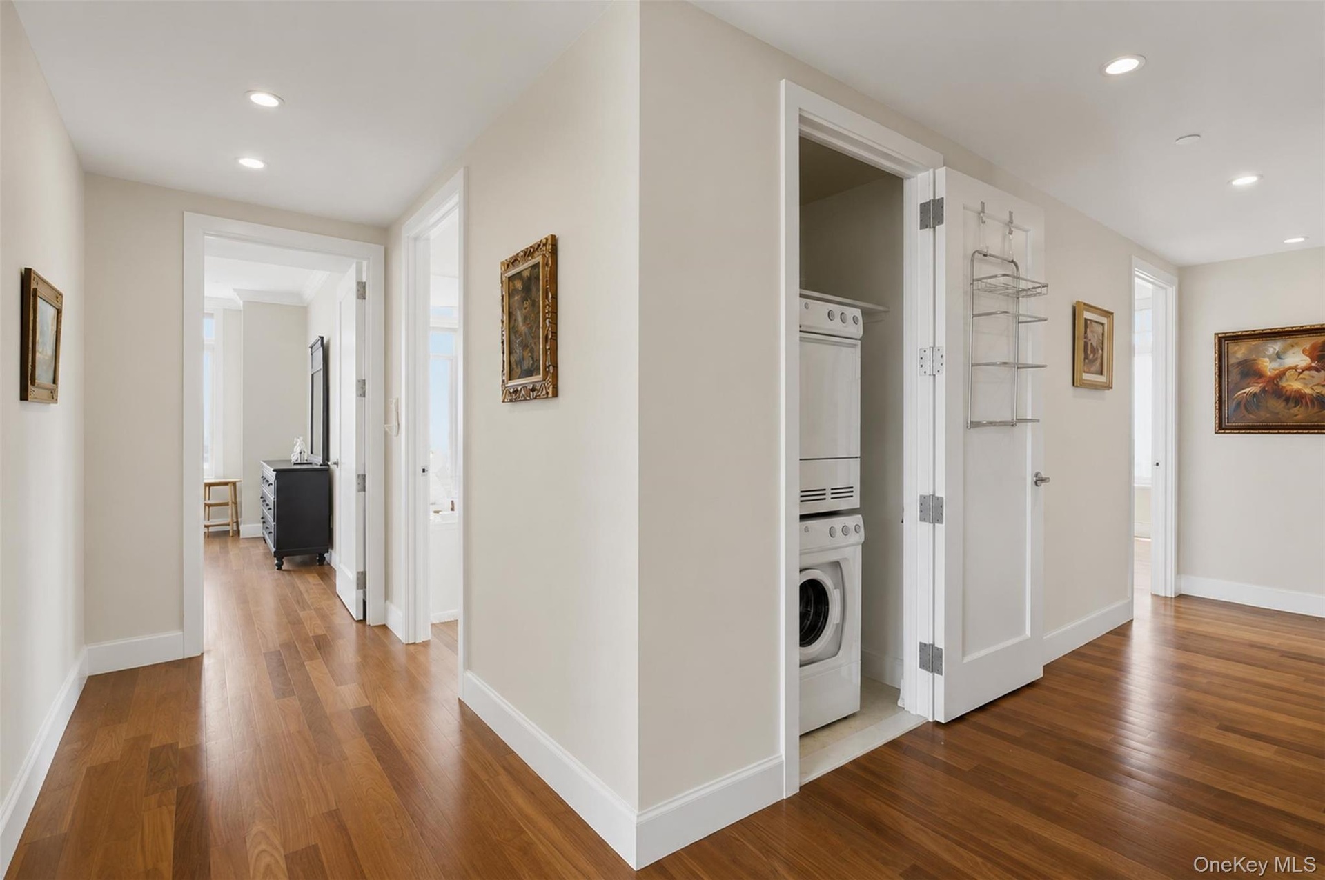 Hallway featuring wood-finish flooring, recessed lighting, and a stacked washer and dryer unit