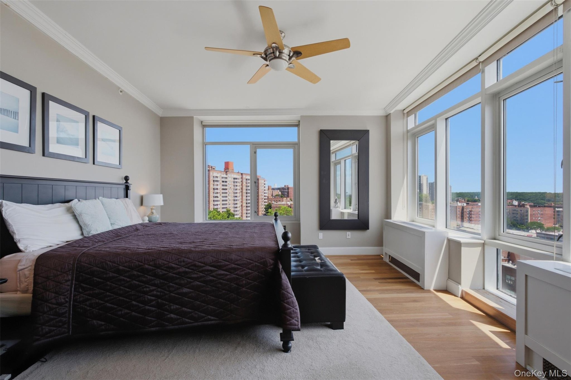Spacious primary bedroom featuring extensive window-lines, light wood-finish flooring, and a ceiling fan
