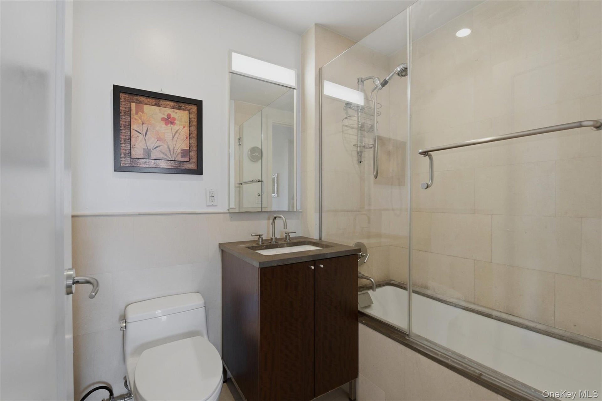 Bathroom featuring a dark wood-finish vanity with a single basin sink and wall-mounted mirror