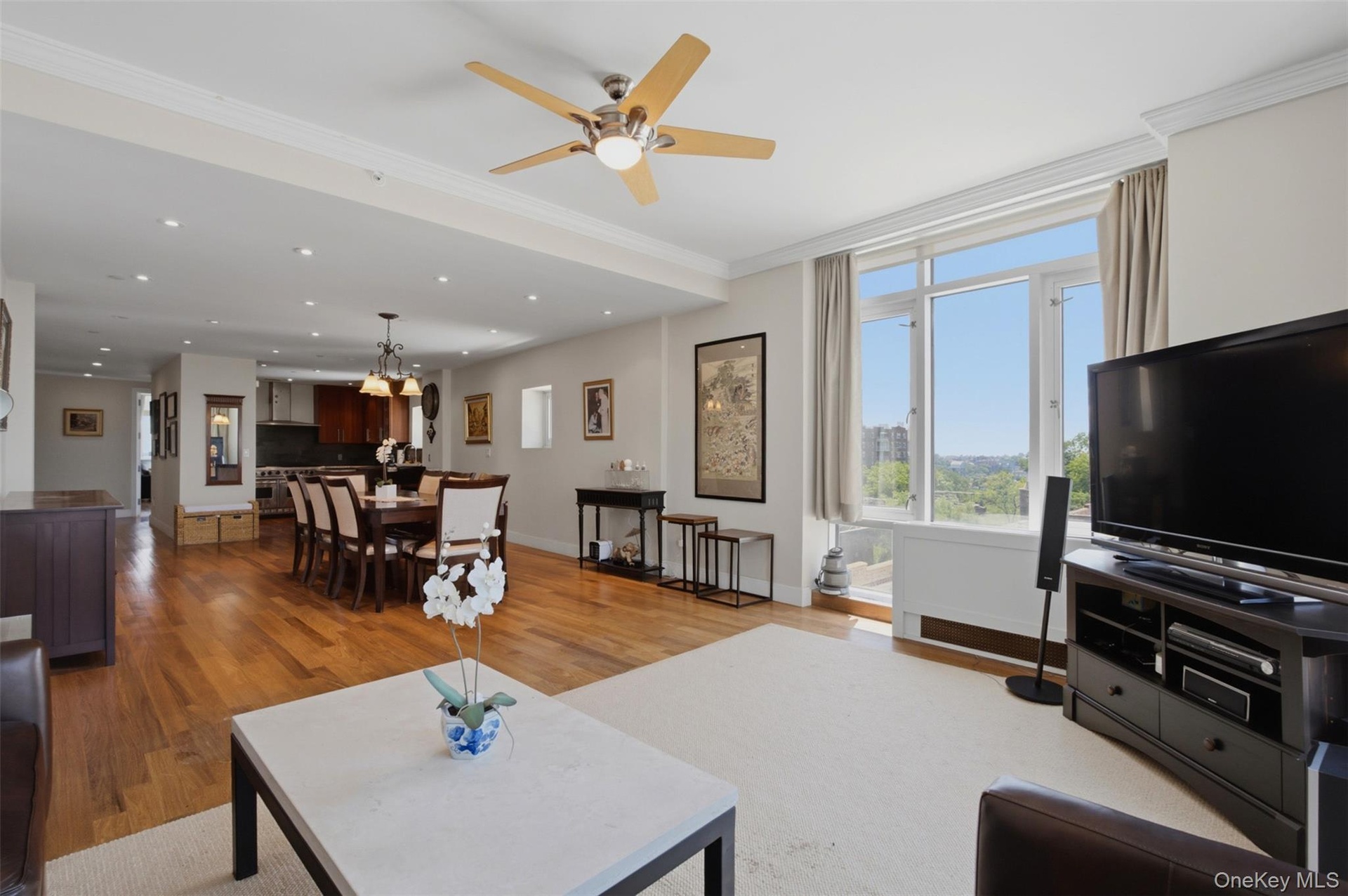 Open-concept living area with abundant natural light, crown molding, and wood-finish flooring