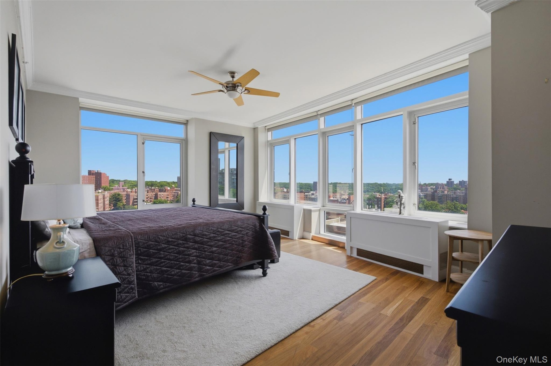 Primary bedroom with expansive window wall with cityscape and green space panorama
