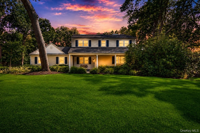 Two-story residence featuring a covered front porch, dark shutters, and white window trim