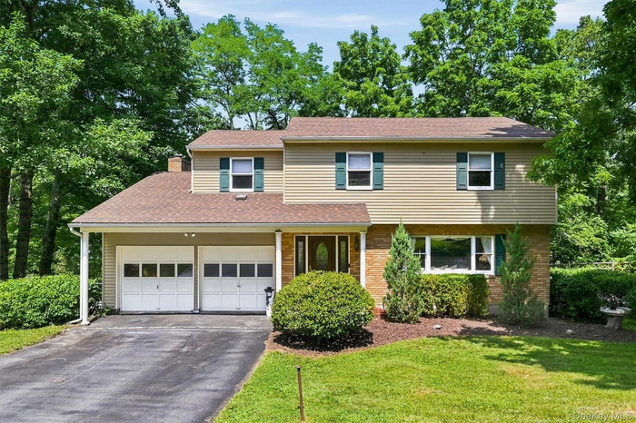 Split-level home featuring a two-car garage with overhead doors