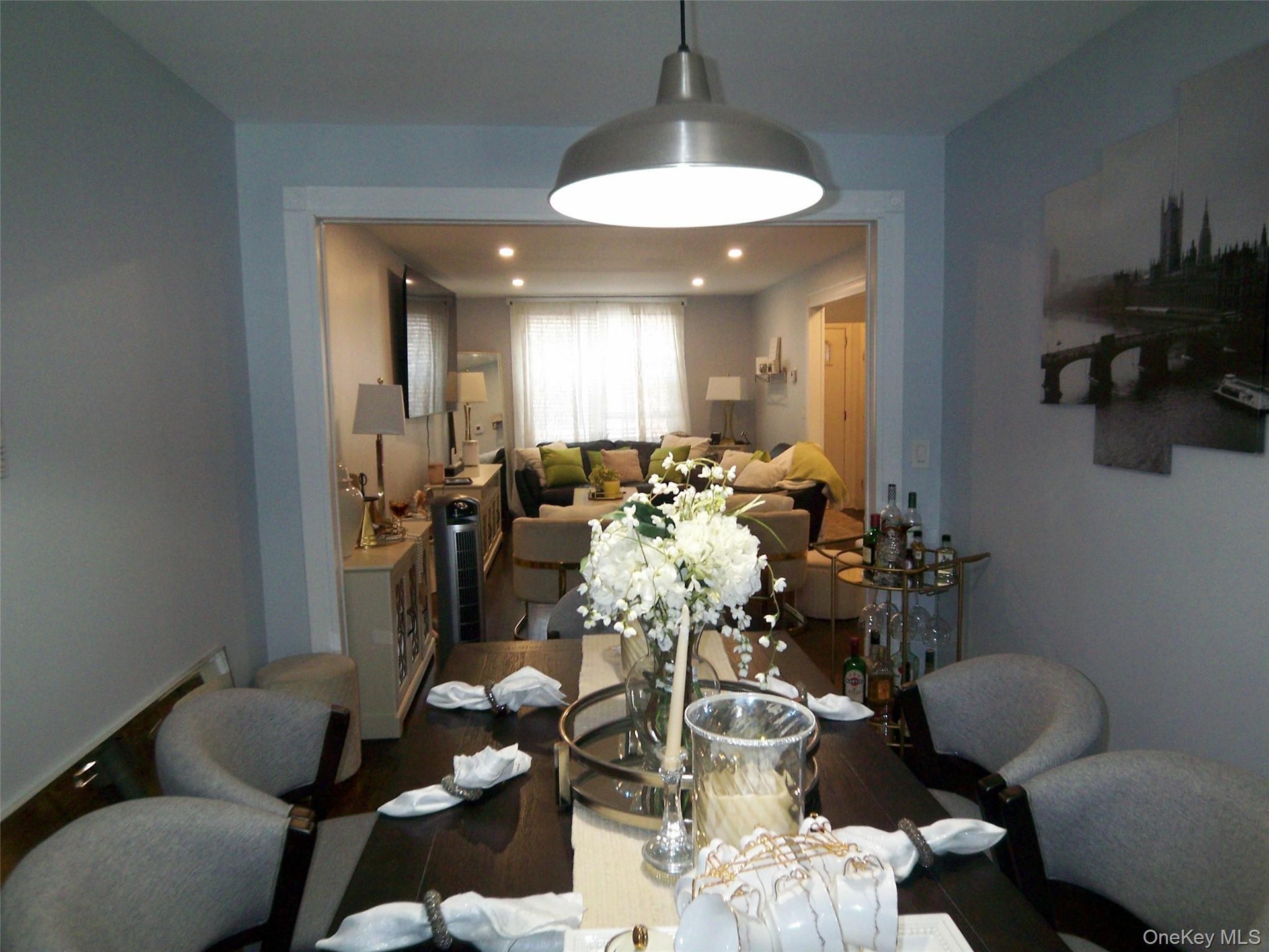 Dining area featuring a dark wood-finish table, upholstered seating, and a brushed metal pendant light fixture