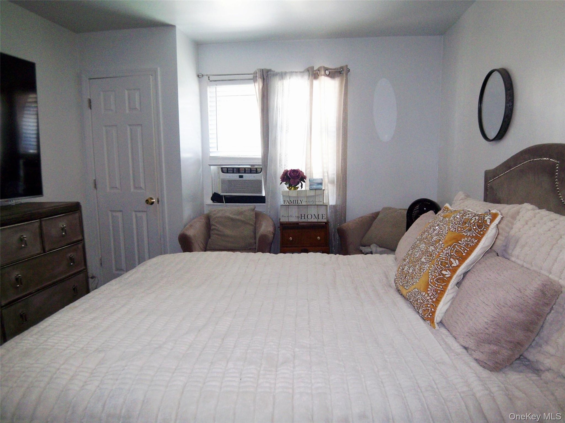 Bedroom featuring a multi-panel door, window with blinds and drapes, and a built-in air conditioning unit