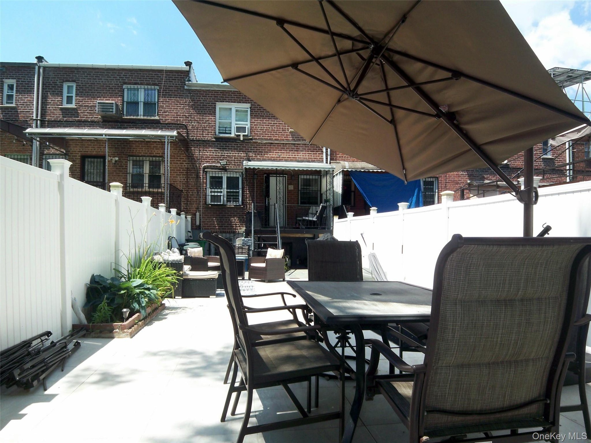 Paved outdoor patio featuring a white privacy fence and a built-in planter box