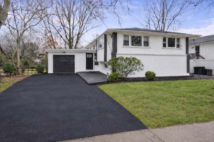 Modern split-level residence featuring a white facade with dark trim accents