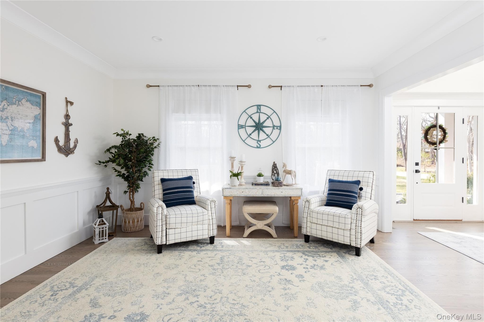 Living area with wood finished floors, ornamental molding, wainscoting, and a decorative wall