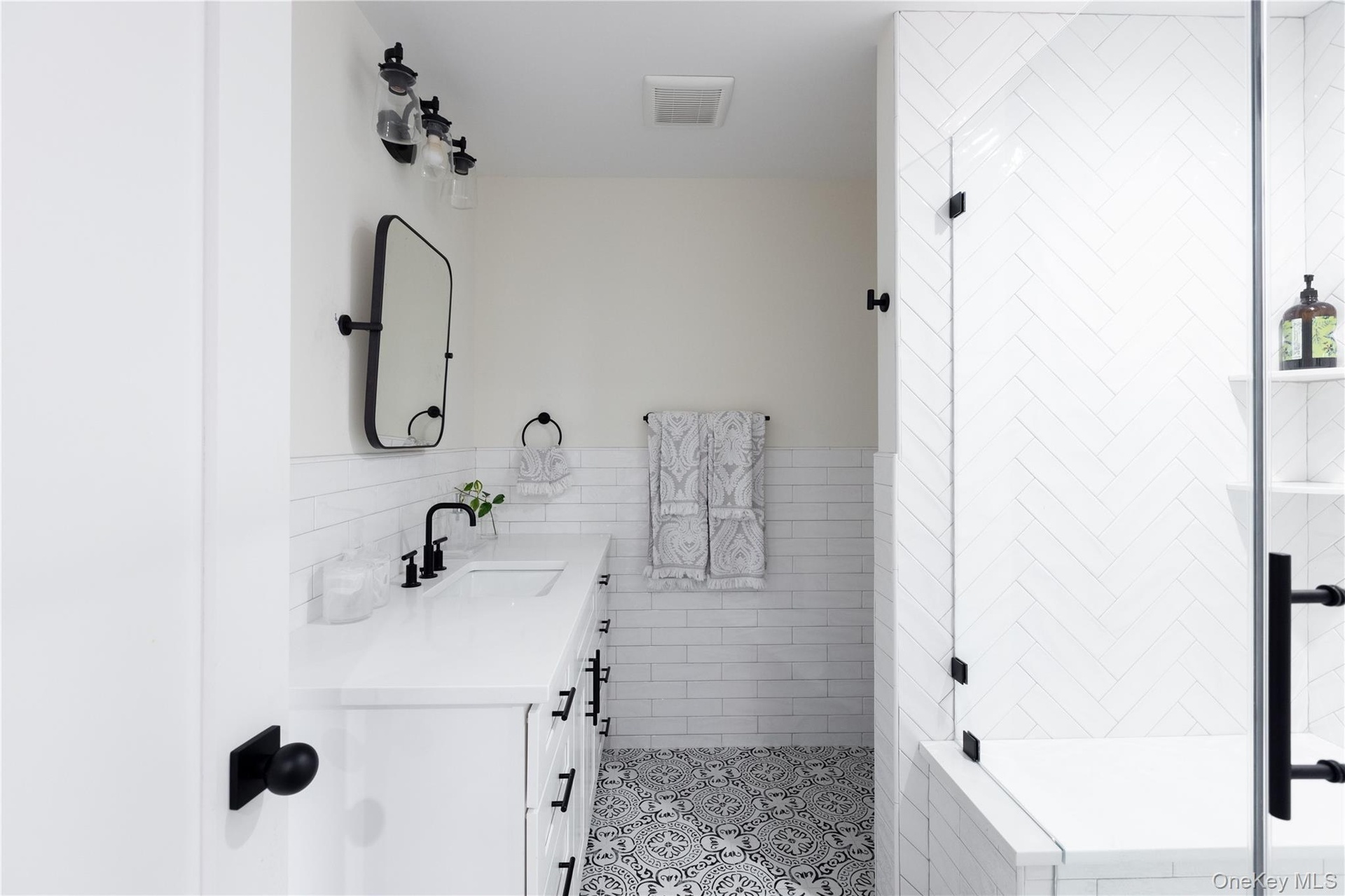 Full bathroom with tile walls, vanity, a stall shower, wainscoting, and light tile patterned floors