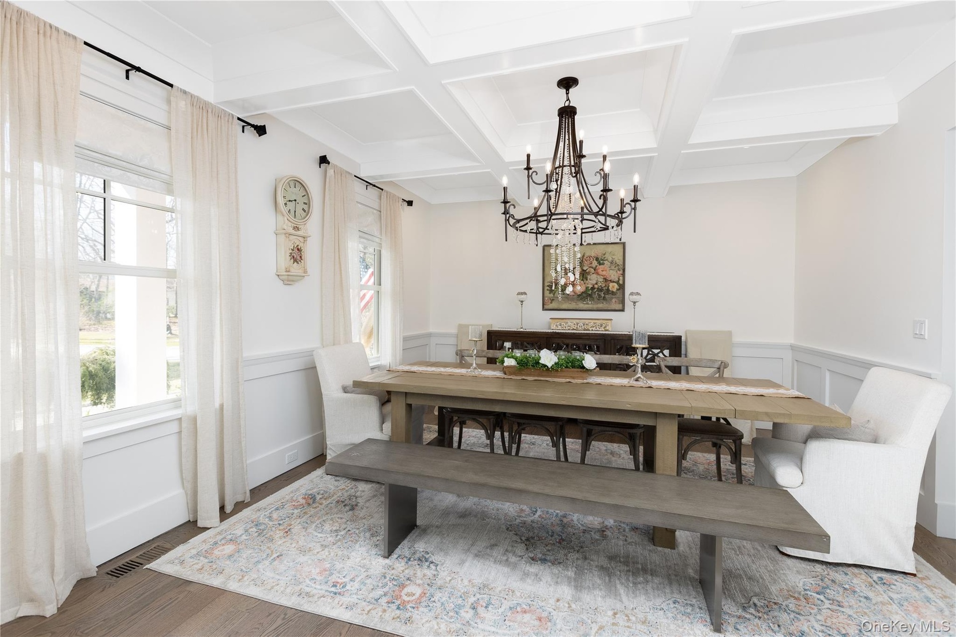 Dining space with beam ceiling, wood finished floors, coffered ceiling, a chandelier, and wainscoting