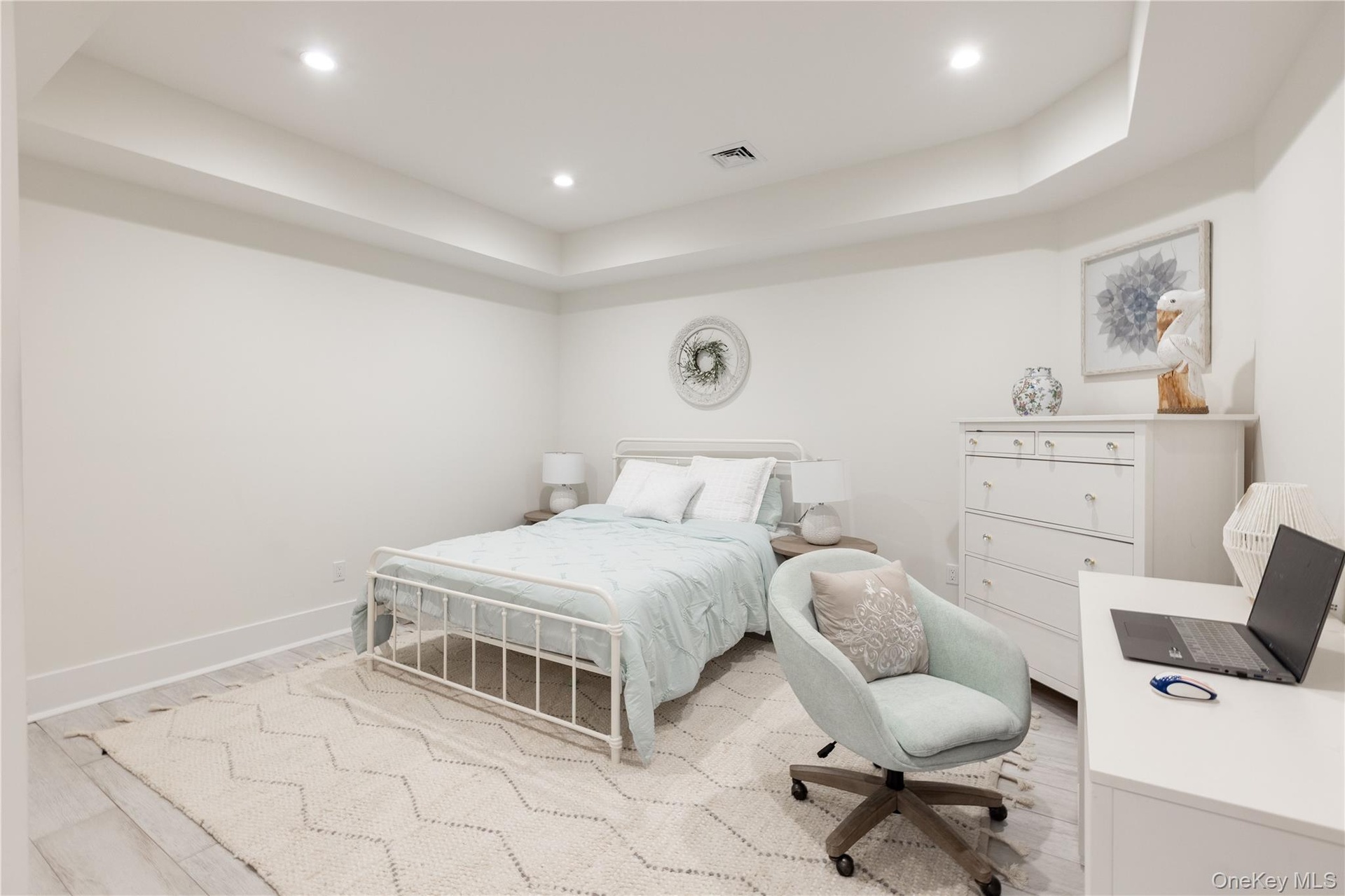Bedroom with a raised ceiling, wood finished floors, and recessed lighting