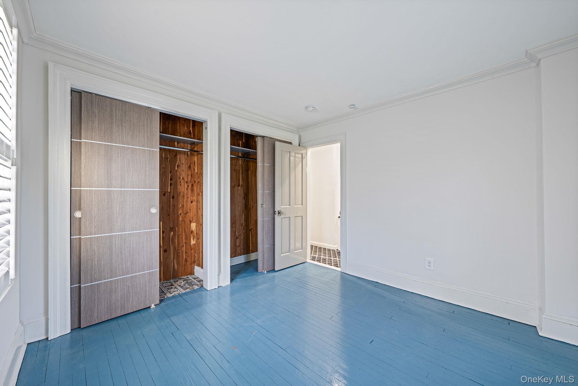 Unfurnished bedroom featuring hardwood / wood-style floors, multiple closets, and ornamental molding