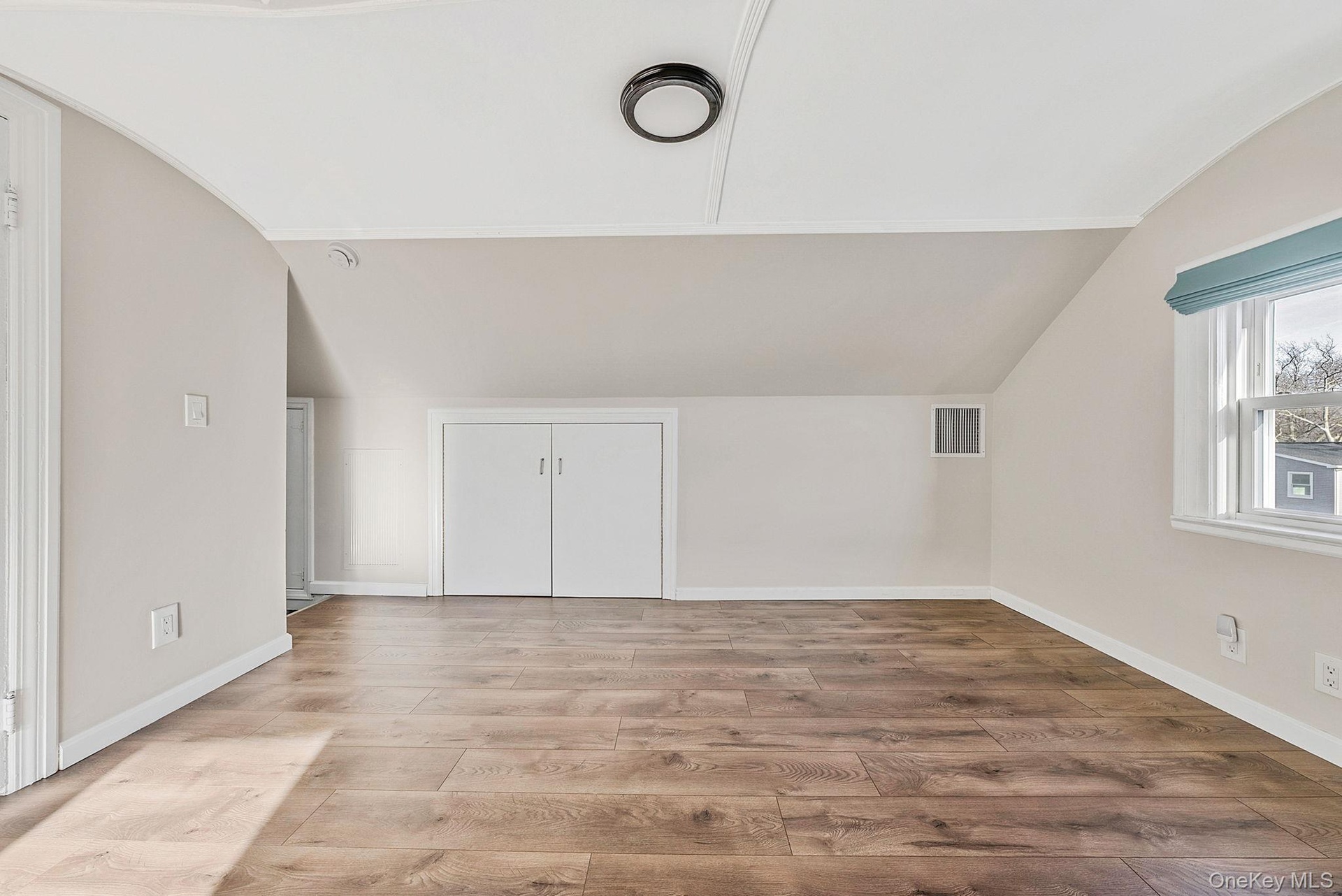Additional living space featuring vaulted ceiling, wood finished floors, and arched walkways