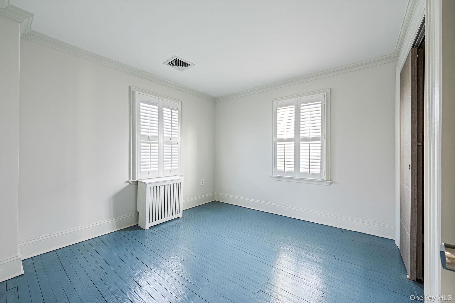 Unfurnished bedroom featuring multiple windows, crown molding, radiator, and dark wood-style flooring