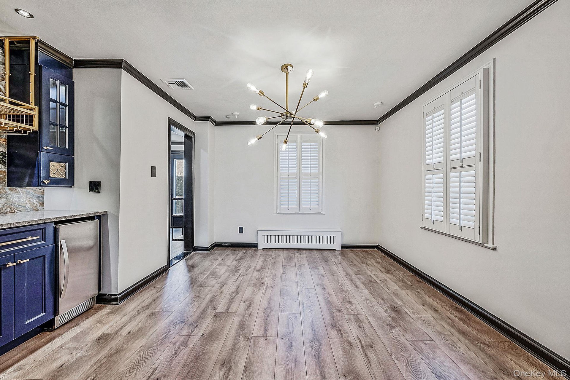 Unfurnished dining area featuring a chandelier, ornamental molding, light wood-style flooring, and radiator