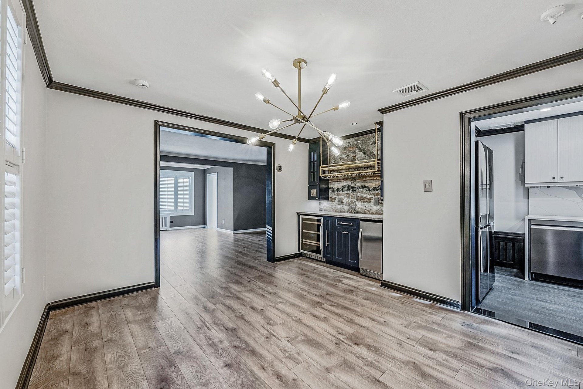 Kitchen with ornamental molding, stainless steel appliances, backsplash, glass insert cabinets, and light wood-style flooring
