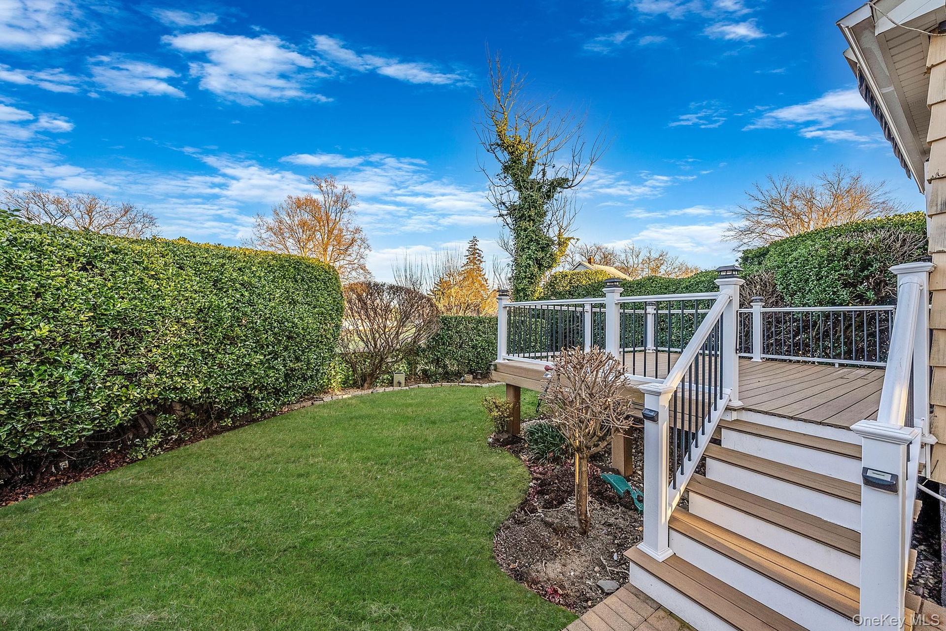 View of grassy yard featuring a deck and stairway