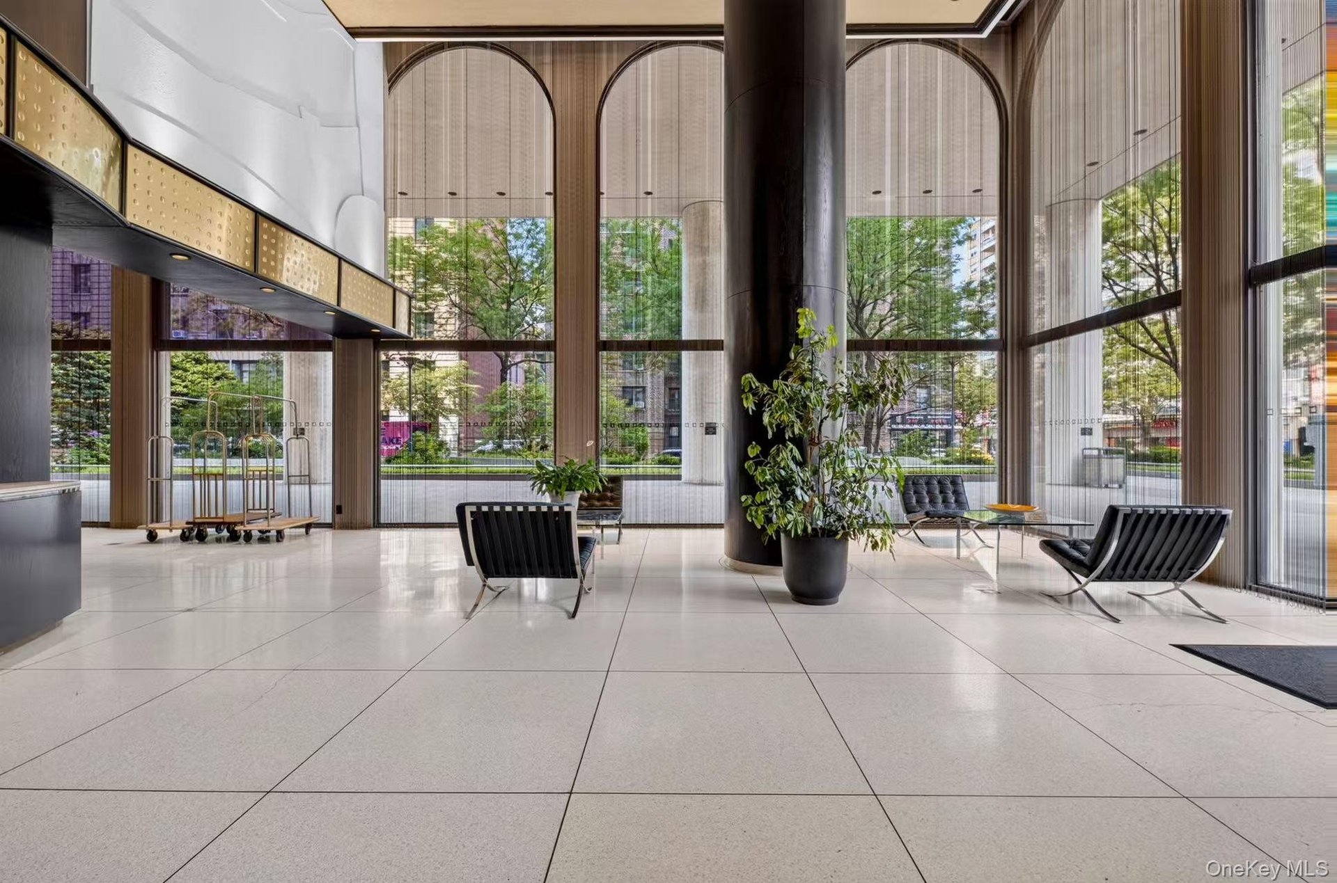 Spacious lobby featuring polished tiled flooring, floor-to-ceiling arched windows, and a prominent dark architectural column