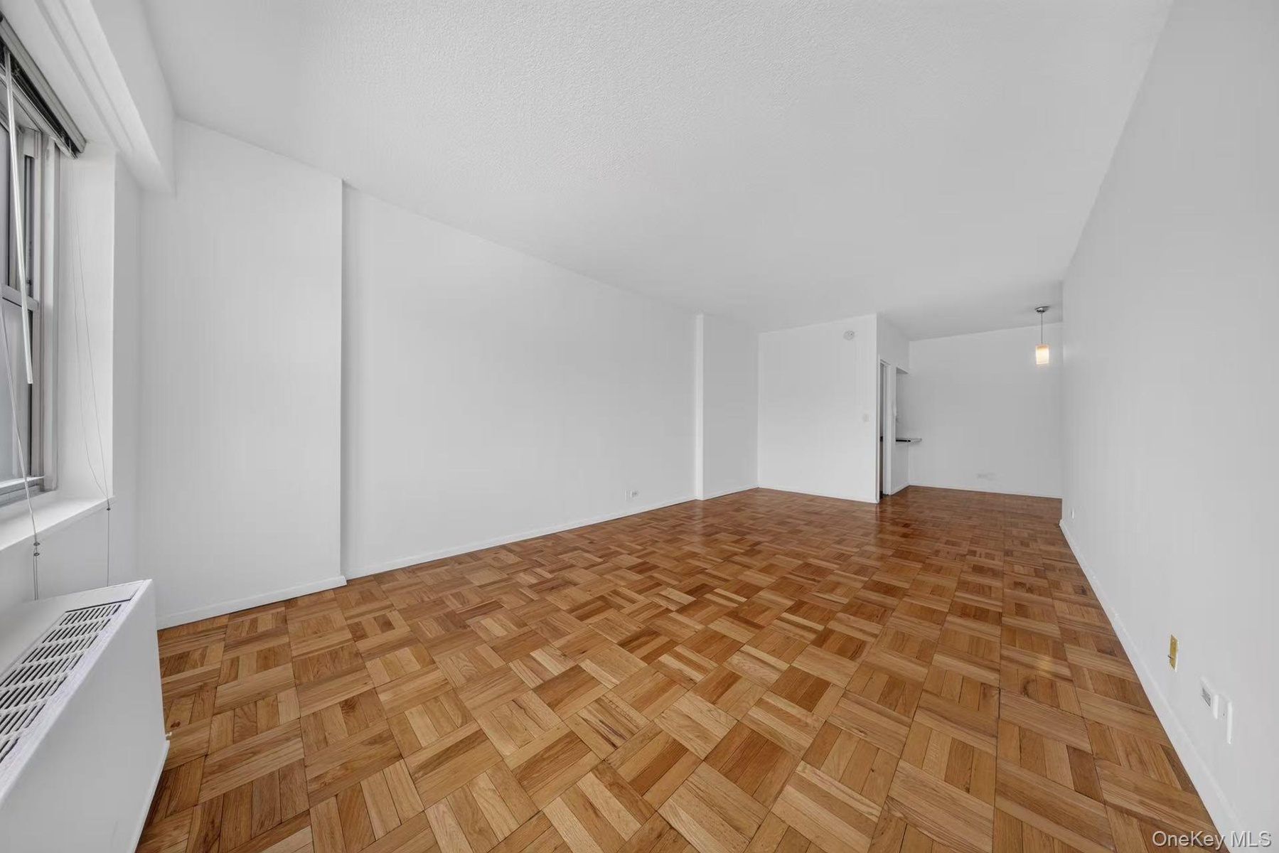 Expansive living space featuring parquet wood flooring and crisp white walls