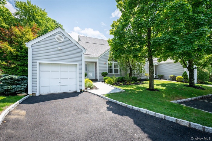 Siding exterior with an attached garage, paved driveway, and manicured landscaping