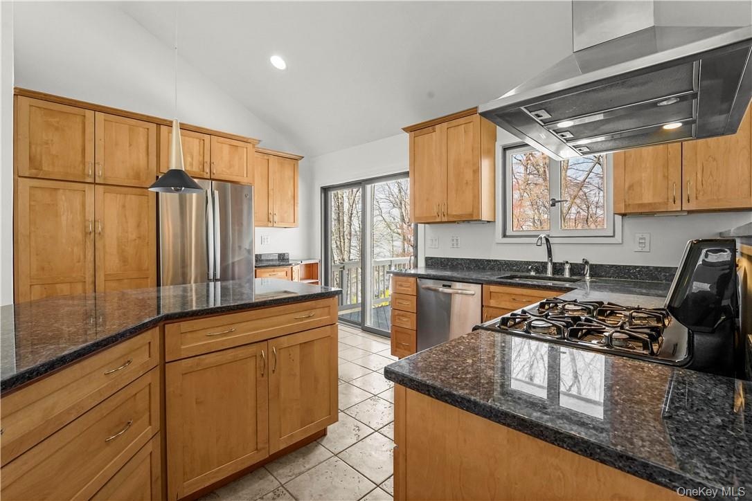 Kitchen with stainless appliances, gas stove, granite counters and sliding glass door to deck.