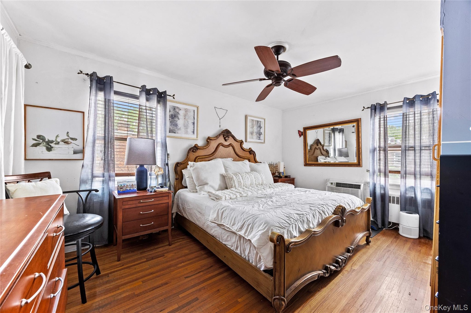 Bedroom 1 - Hardwood flooring, ceiling fan with light fixture, multiple windows with blinds, and white walls