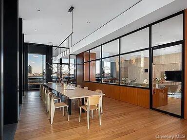 Spacious interior with wood-finish flooring, a contemporary linear chandelier, and floor-to-ceiling windows