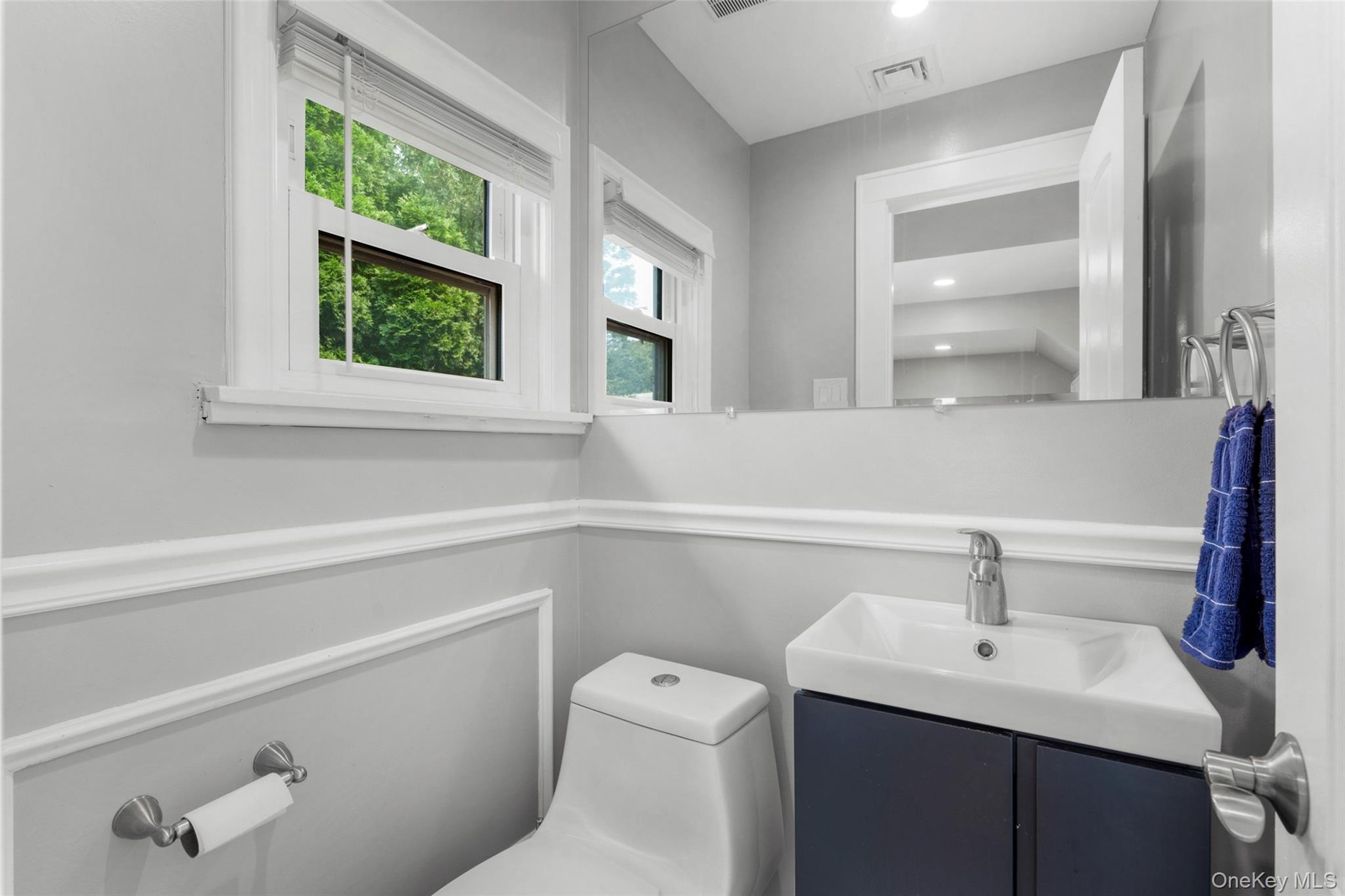Contemporary bathroom featuring a wall-mounted vanity with integrated sink, chrome faucet, and full-width mirror