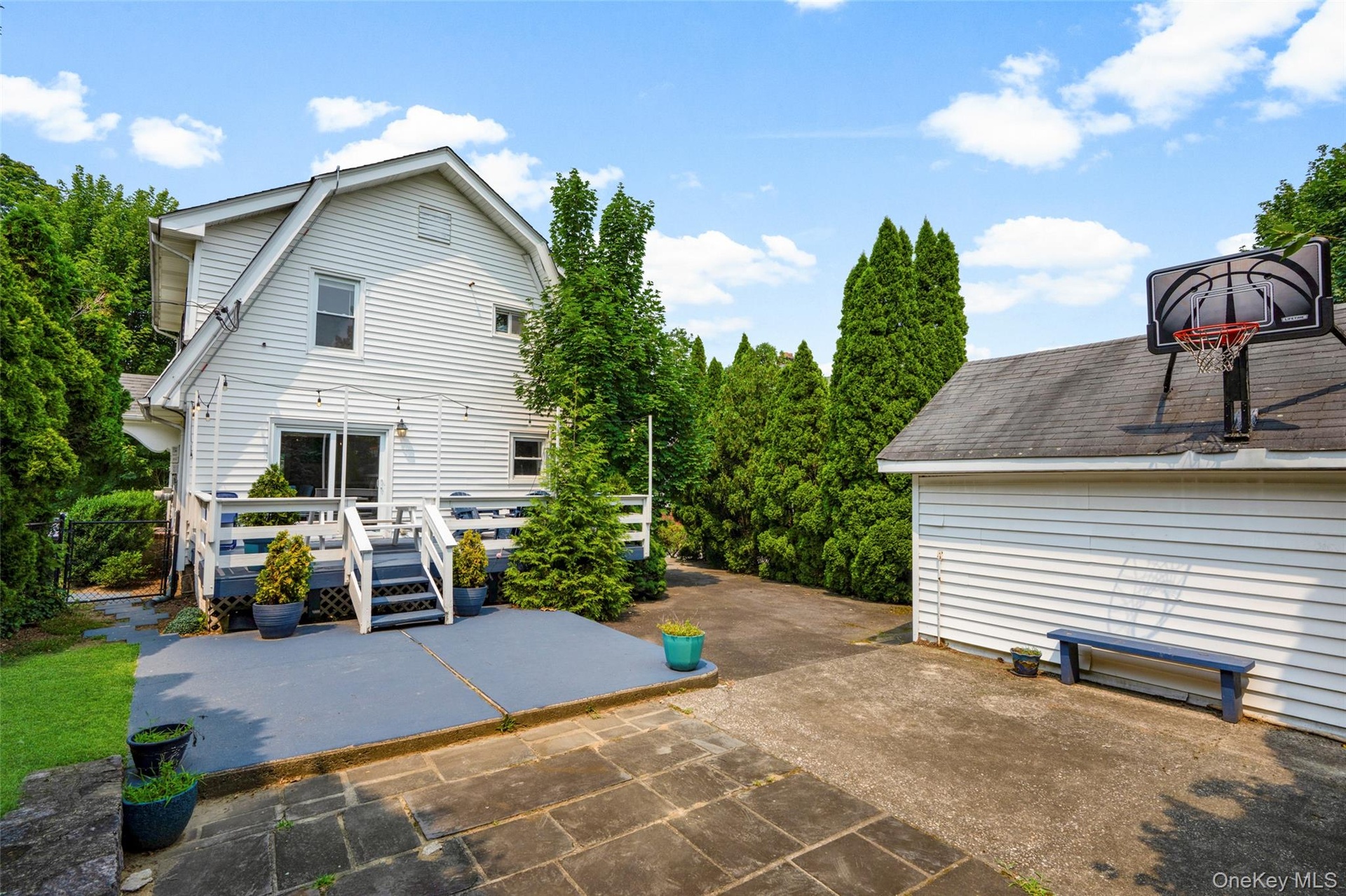 Rear exterior featuring a multi-level deck with white railings, a concrete patio, and even a basketball hoop!