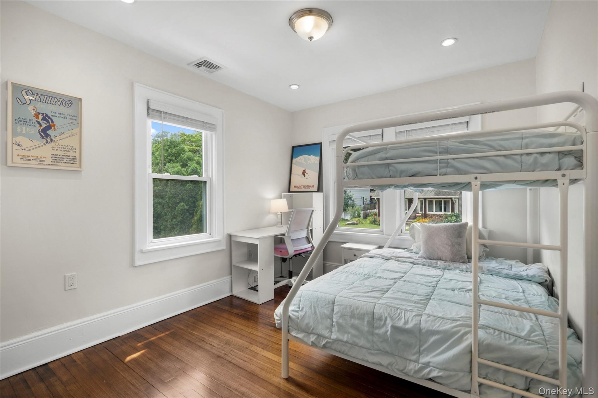 Bright bedroom featuring hardwood flooring, white trim, recessed lighting, and a double exposure.