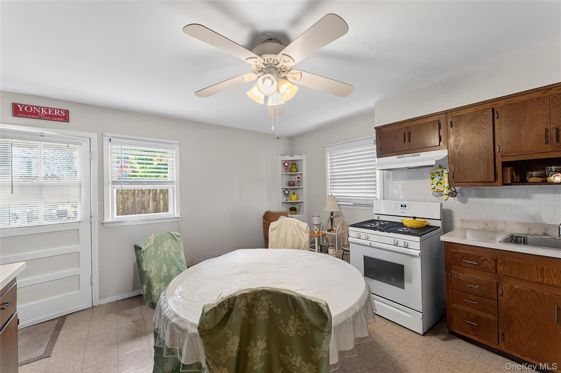 Eat-in kitchen featuring wood cabinetry, a white gas range with overhead ventilation, and a white subway tile backsplash