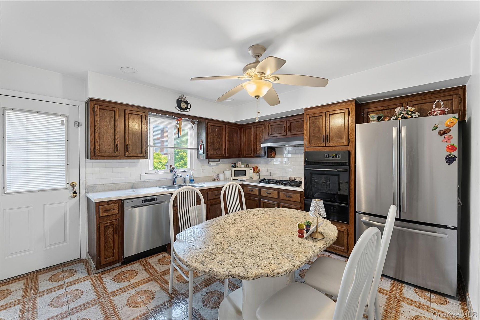 Kitchen featuring wood cabinetry, white subway tile backsplash, and light-toned countertops