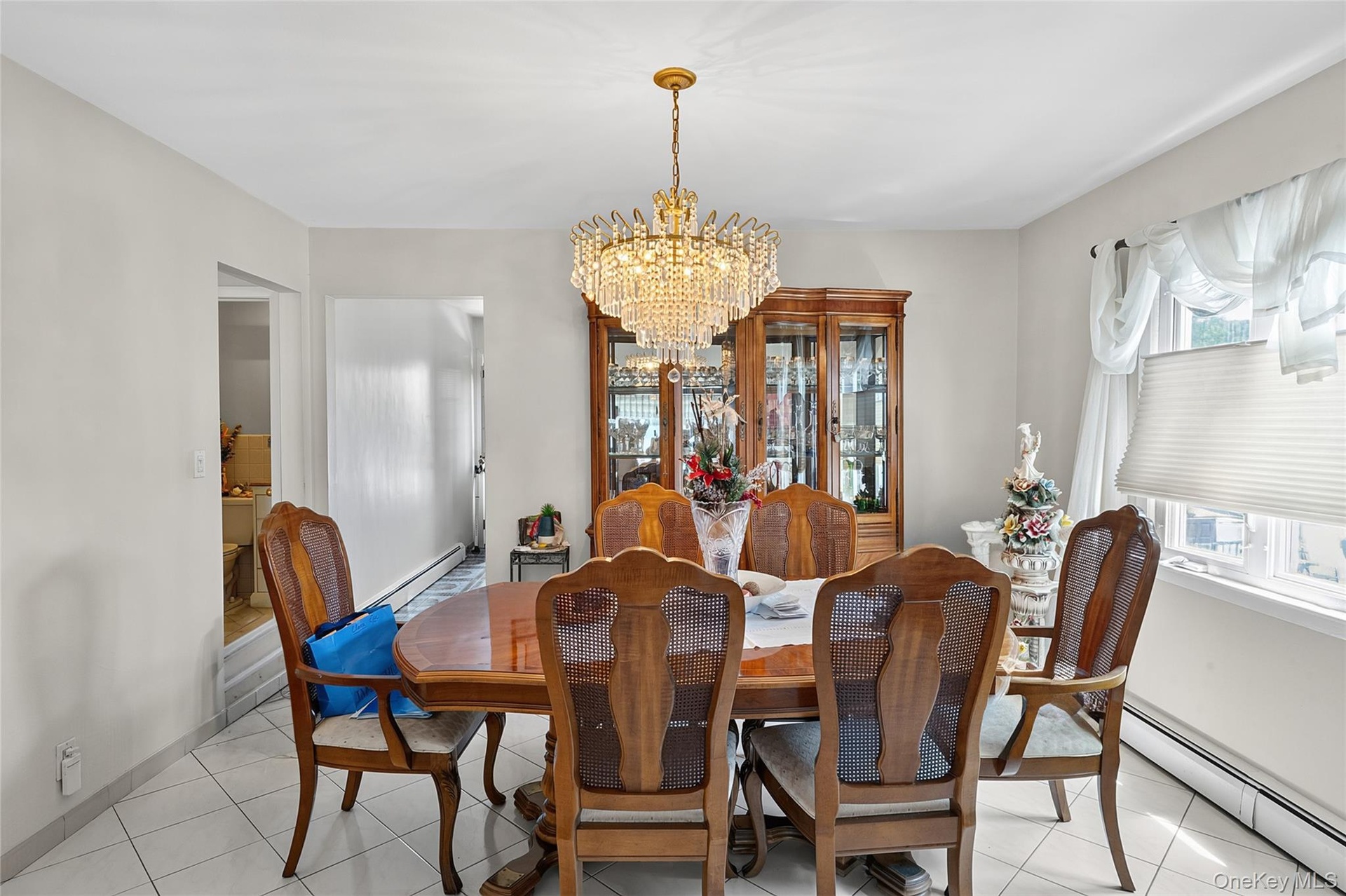 Dining area featuring a central crystal chandelier, tiled flooring, and neutral wall tones