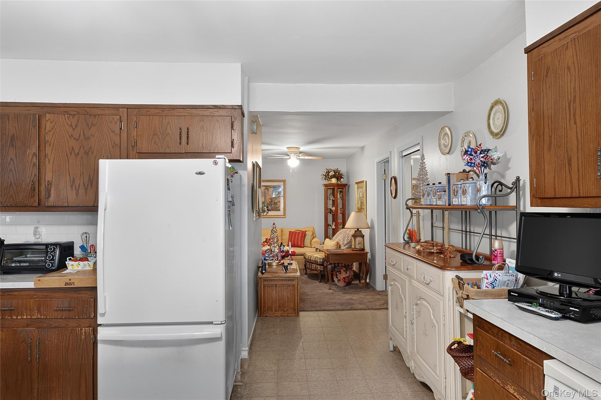 Galley kitchen featuring wood-finish cabinetry, white appliances, and a tiled floor