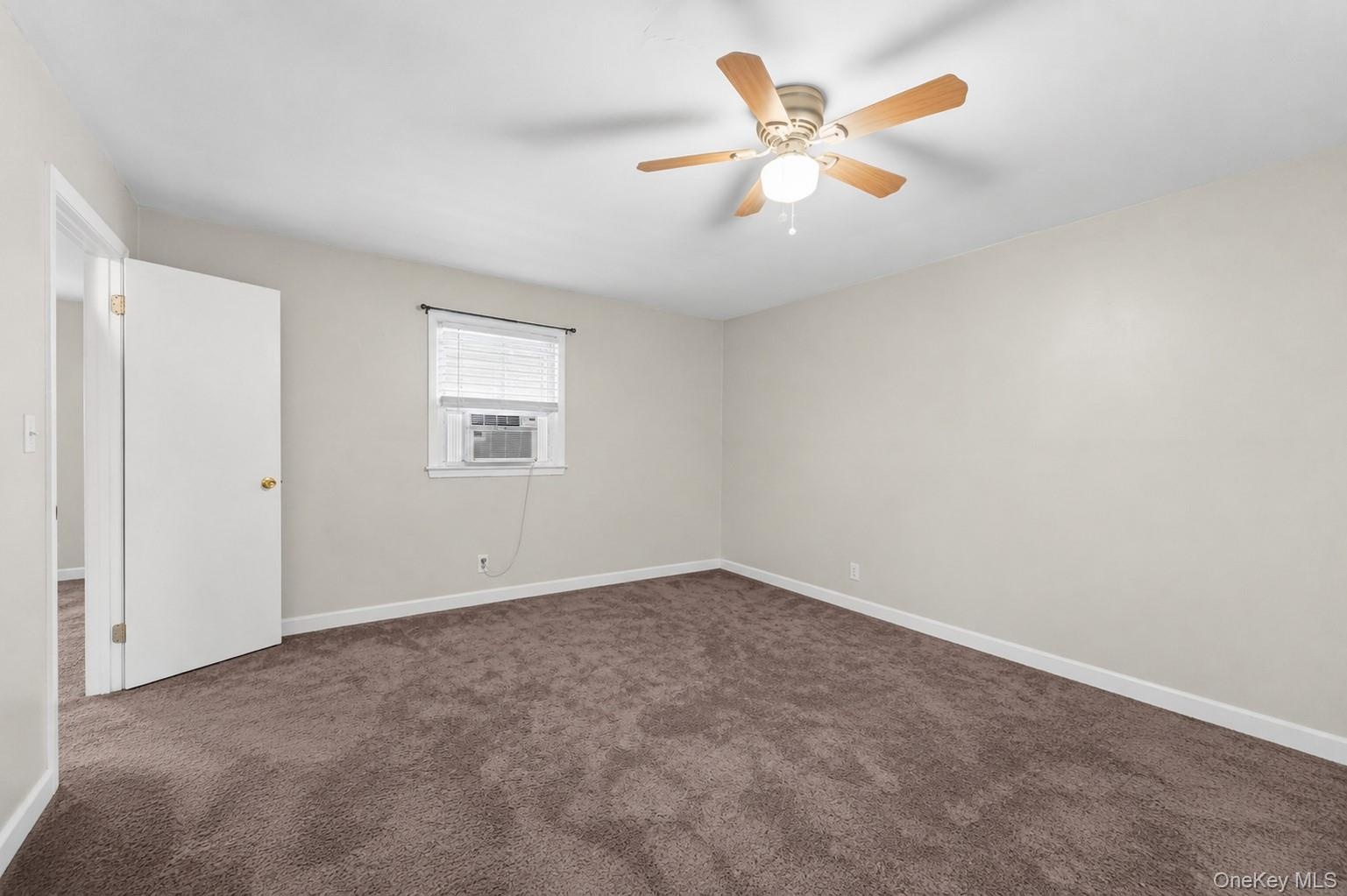 Spacious room featuring neutral wall tones, brown carpeting, a window with horizontal blinds, and a ceiling fan with light fixture