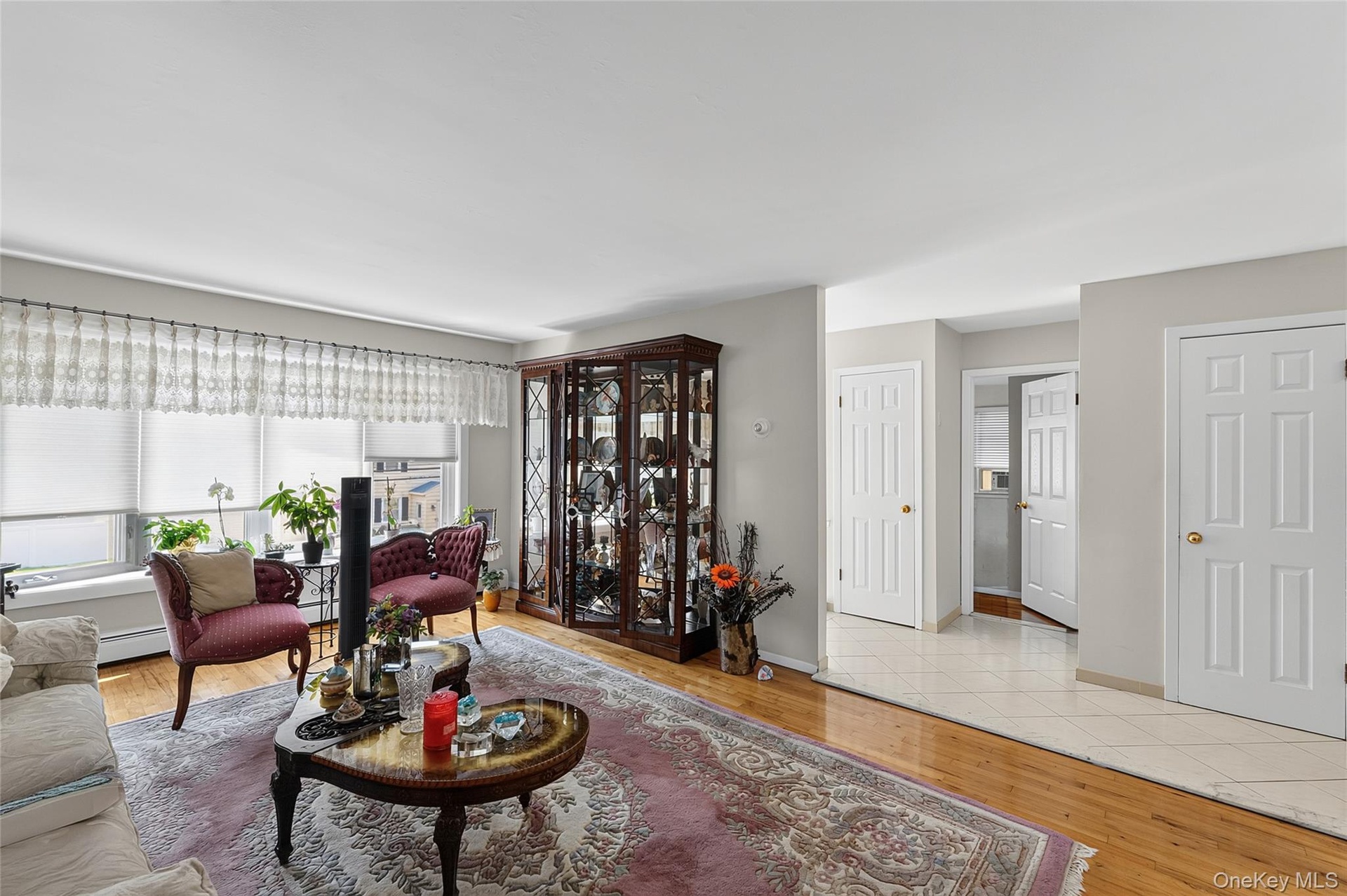 Hardwood flooring extends throughout the living area, complemented by a large window with roller shades