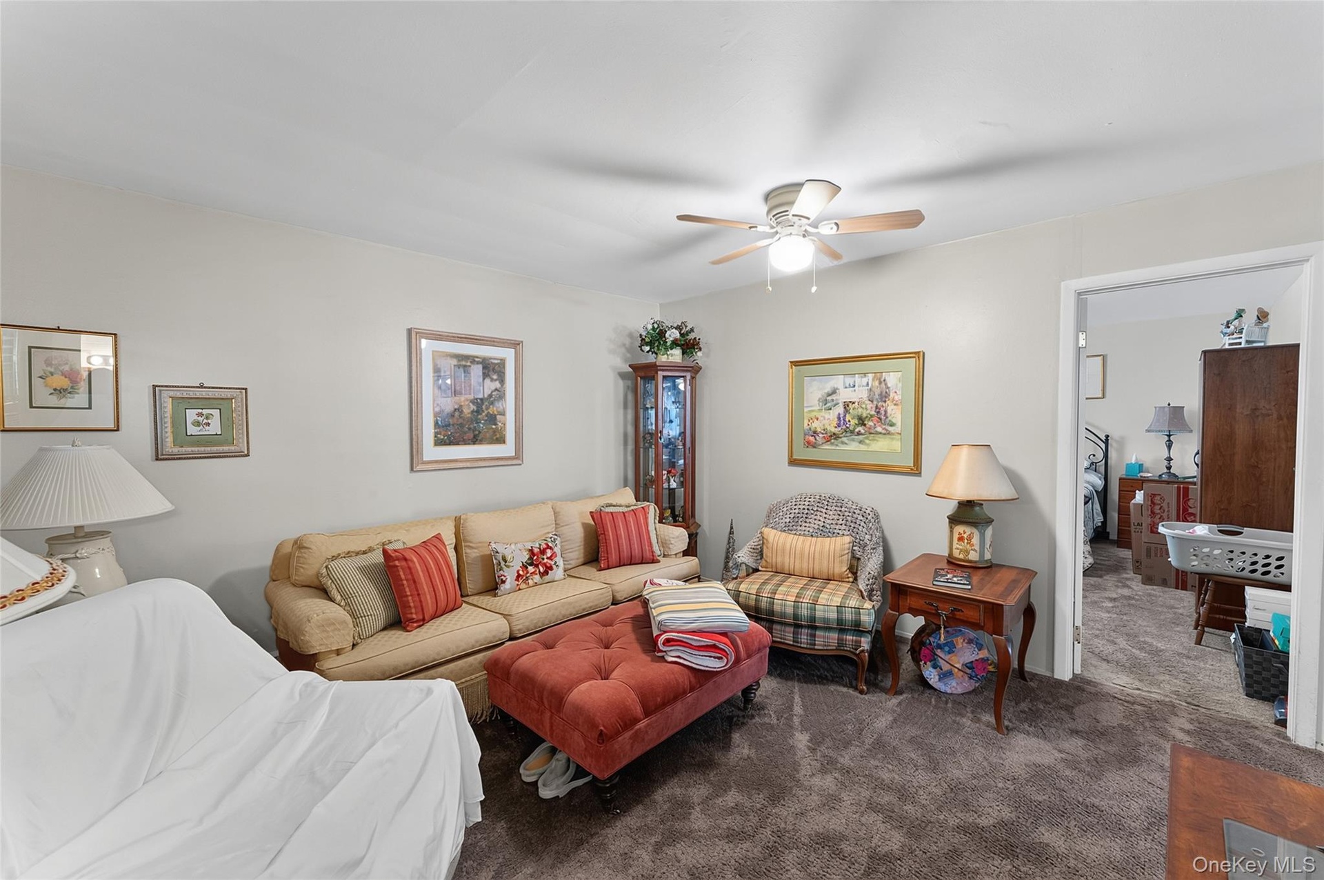 Living area featuring neutral wall paint, ceiling fan with integrated lighting, and carpet flooring
