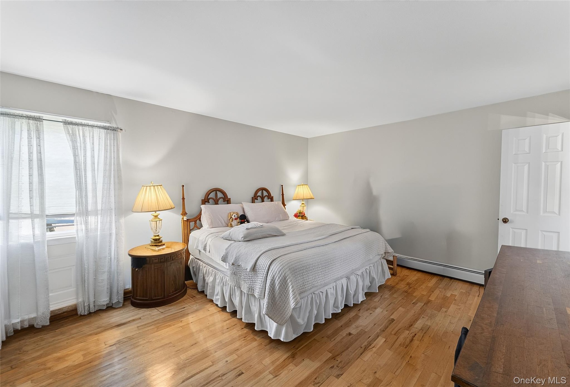 Room featuring wood-finish flooring, a full-height window, light-toned walls, and a white paneled door