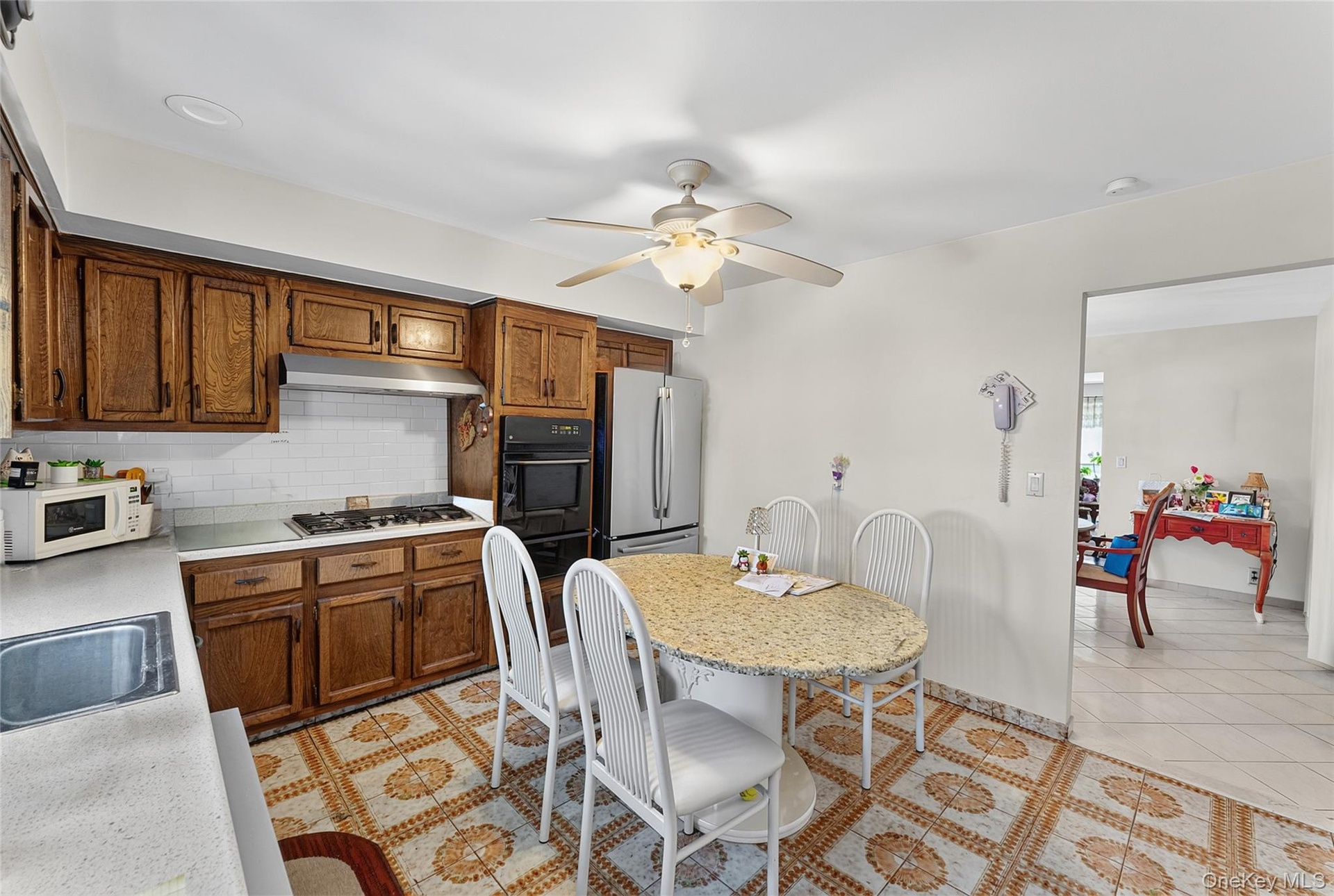 Kitchen featuring wood cabinetry, white subway tile backsplash, and patterned floor tile