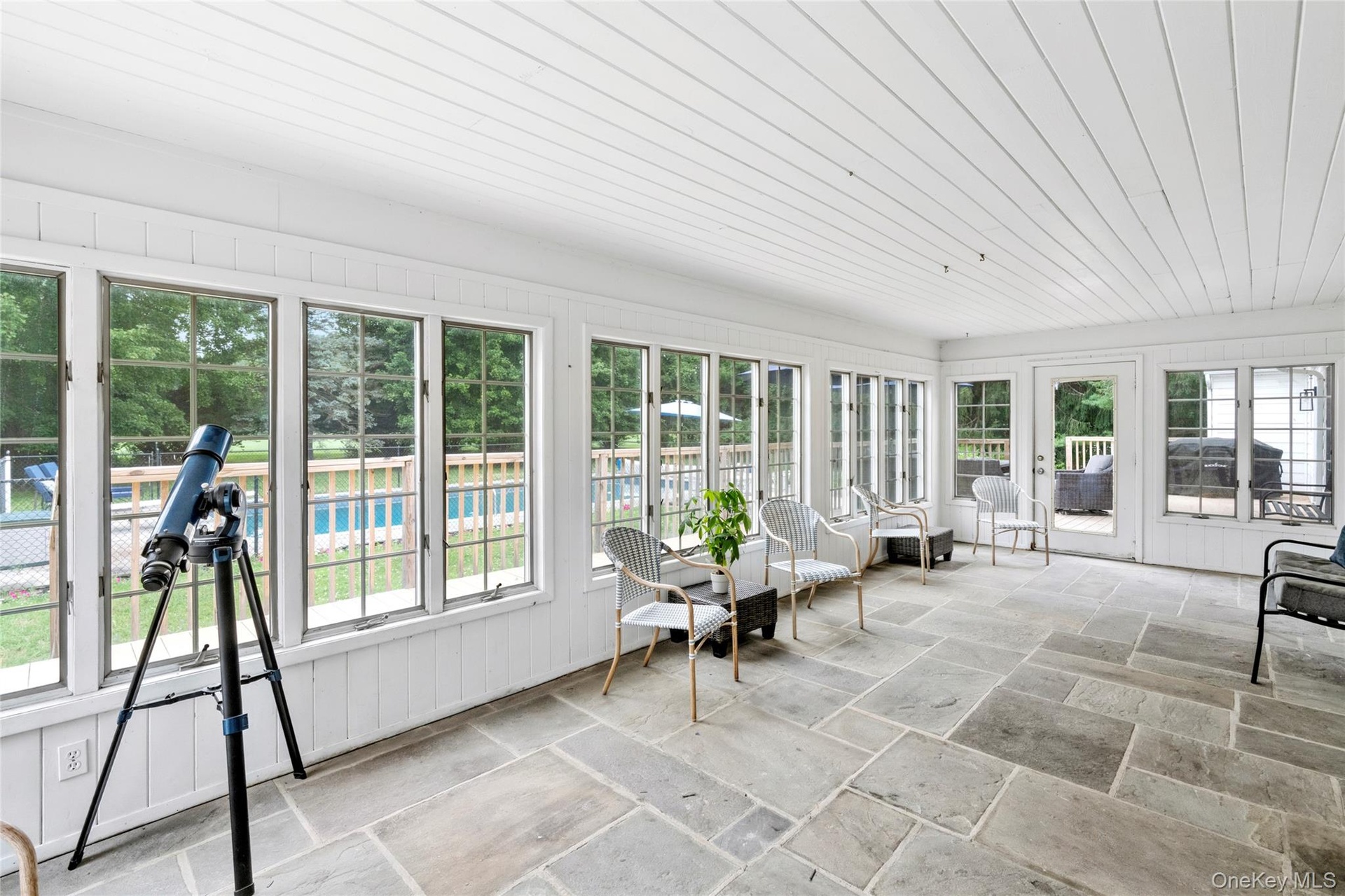 An expansive sun filled enclosed porch offering beautiful views of the surrounding landscape.