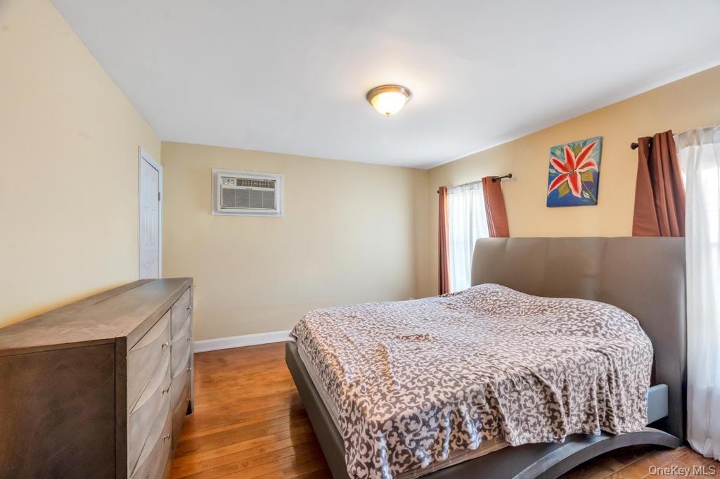 Spacious room featuring wood-finish flooring and a window-mounted air conditioning unit
