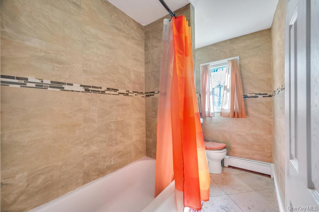 Bathtub with a tiled surround featuring a decorative mosaic accent band