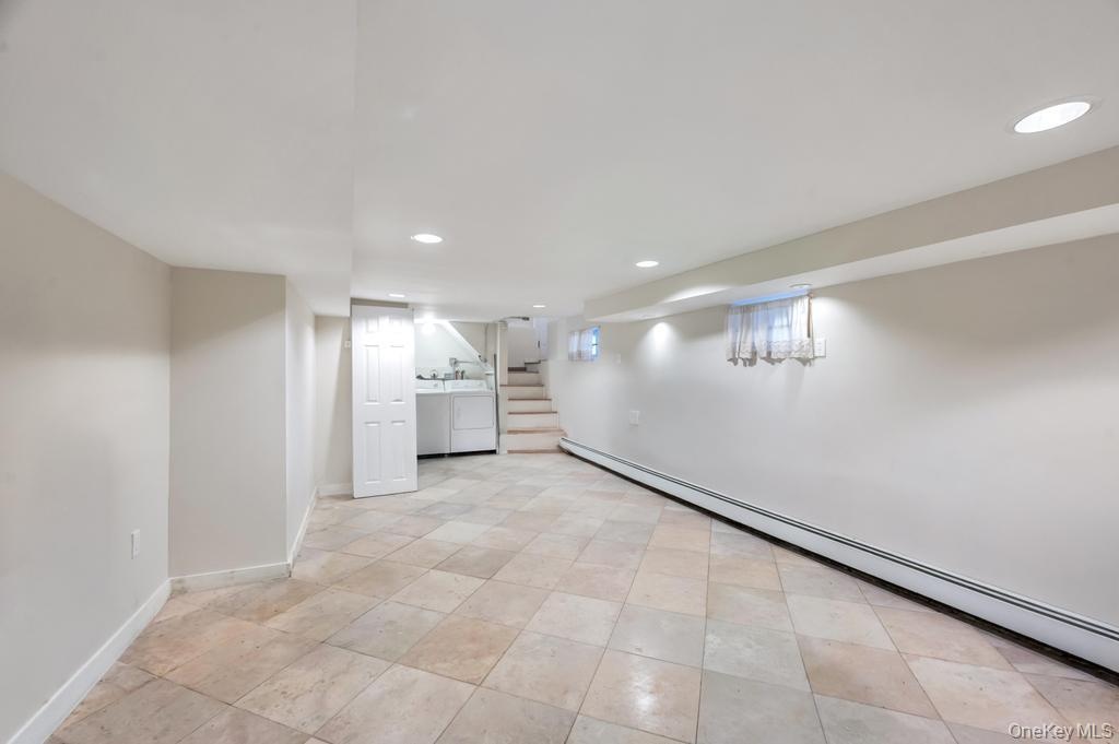 Spacious lower-level area featuring large format tile flooring, recessed lighting, and baseboard heating