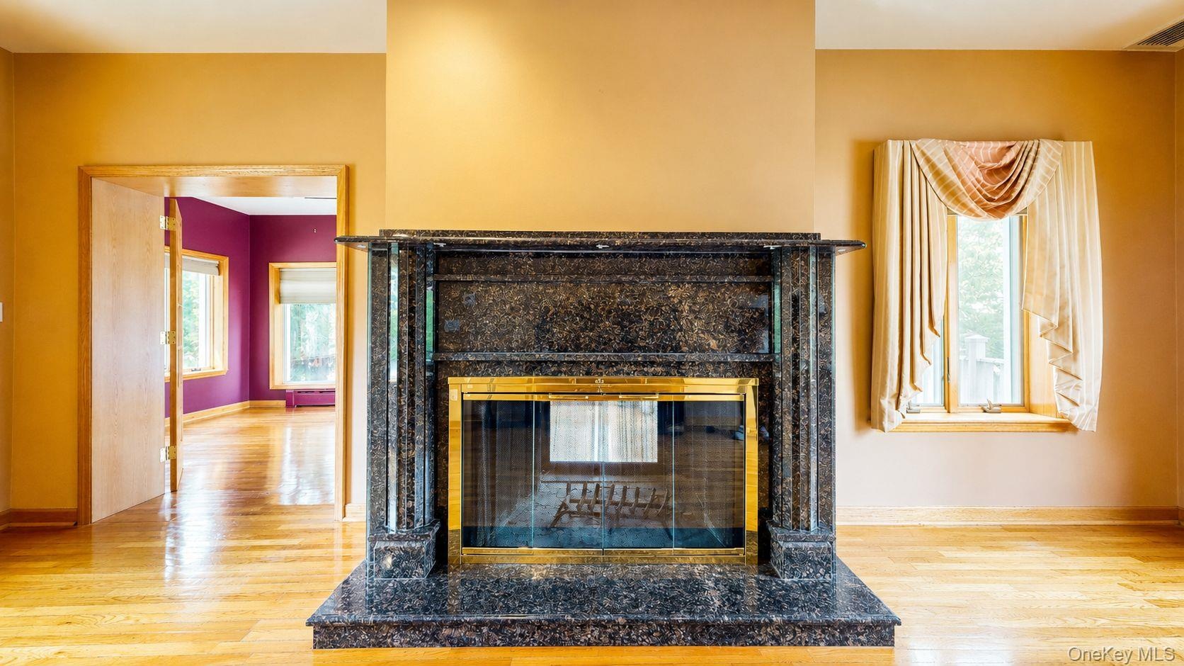 Fireplace featuring a dark granite surround and hearth with a polished brass firebox