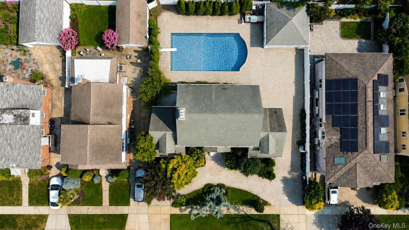 Expansive property featuring a curved inground pool, an extensive paved patio, and mature landscaping