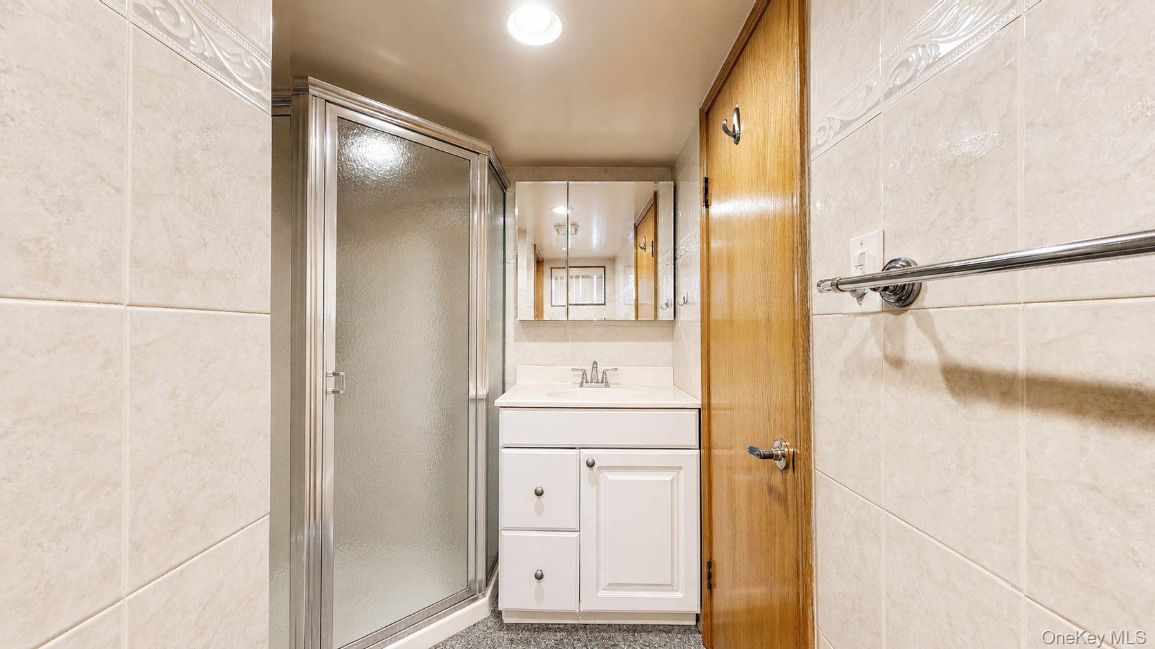 White vanity with a laminate countertop, chrome faucet, and mirrored medicine cabinet