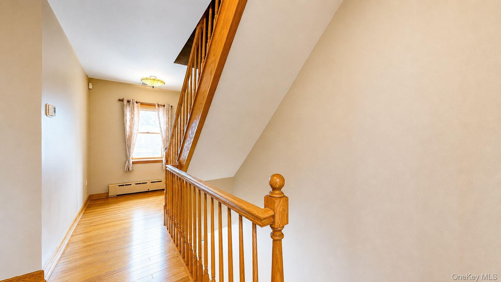 Hardwood flooring extending through the hallway and up the staircase, featuring natural wood banisters and balusters