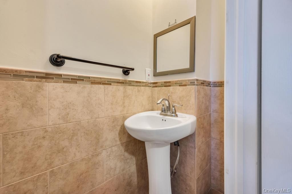 Pedestal sink with chrome faucet, complemented by full-height wall tiling and a decorative mosaic accent strip