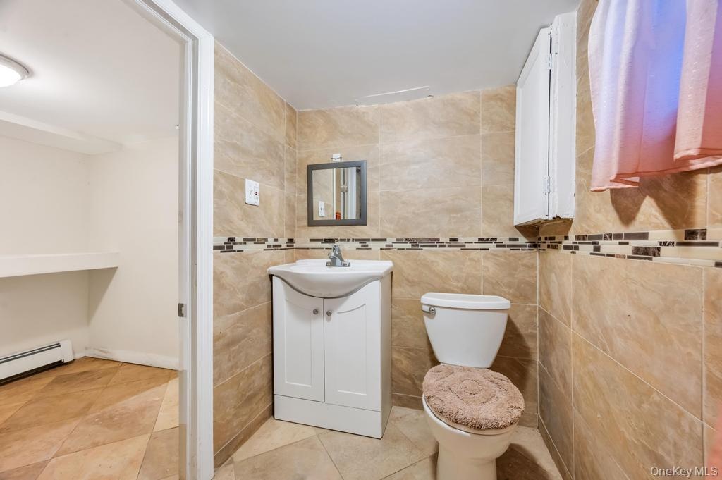 Ceramic tile walls with a decorative mosaic border complement the white vanity with integrated sink and chrome faucet